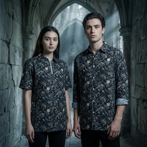May include: Two people wearing matching dark green shirts with a repeating pattern of gargoyles and gothic imagery. The shirt on the left has short sleeves and a zip, while the shirt on the right has long sleeves.