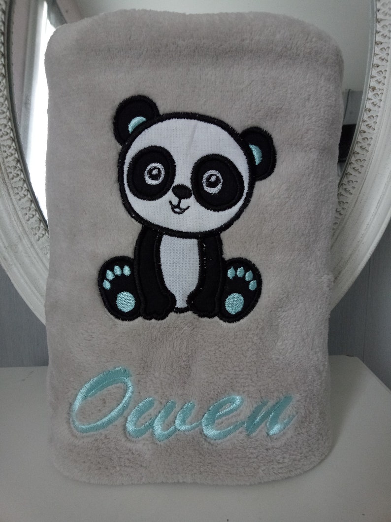 May include: A gray plush blanket with a black and white embroidered panda bear and the name "Owen" in light blue embroidery.