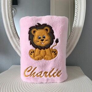May include: Pink plush blanket with an embroidered lion and the name "Charlie" in gold thread.