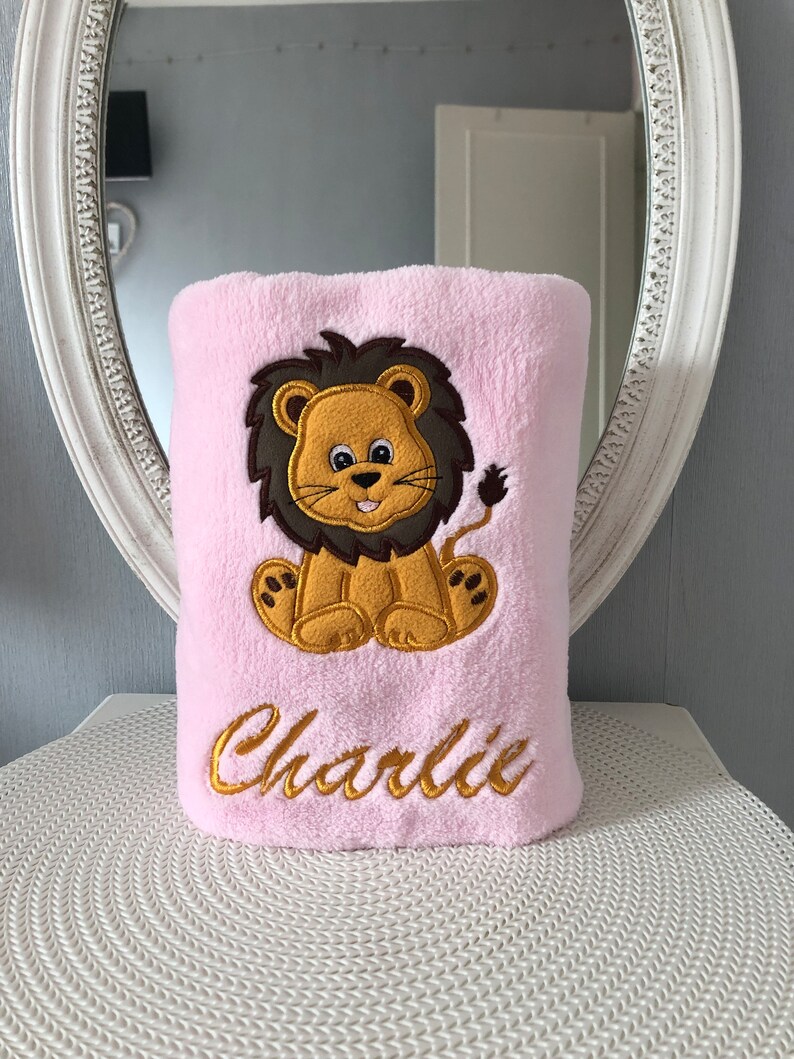 May include: Pink plush blanket with an embroidered lion and the name "Charlie" in gold thread.