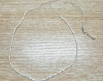 May include: A white pearl necklace with a silver clasp. The necklace is made of small, round pearls and is strung on a thin silver chain.