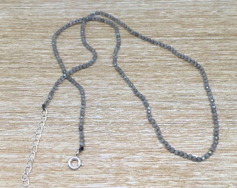May include: A silver chain necklace with a silver clasp. The necklace is made of small, round, gray beads.