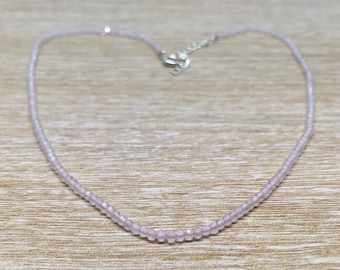 Puede incluir: Un collar delicado hecho de pequeñas cuentas de color rosa claro. El collar está enhebrado en una cadena de plata y tiene un cierre simple.