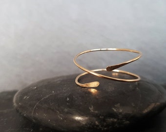 May include: A minimalist gold-toned ring with a twisted design. The ring is made from a single piece of wire that is twisted and then bent into a circle. The ring is simple and elegant, and would make a great gift for someone special.