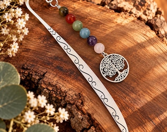 May include: A silver-toned metal bookmark featuring a curved top, engraved scrollwork, and a dangling charm chain. The chain includes six round, multi-colored gemstone beads in dark green, red, light green, blue, purple, and pink, ending in a tree charm.