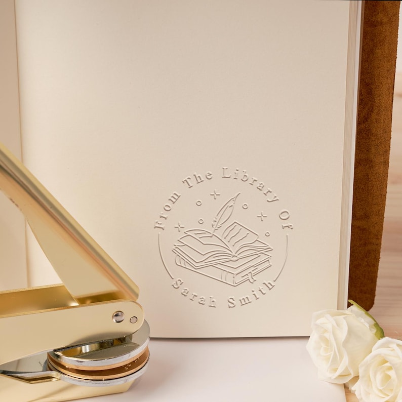 May include: A gold-toned book stamp with a circular design featuring a quill pen and an open book with the text "From The Library Of Sarah Smith".