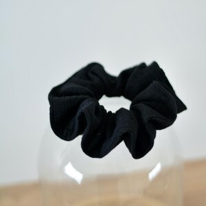 Peut inclure: Un chouchou noir en tissu doux. Le chouchou est de style plissé et bouffant.