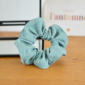 Peut inclure: Un chouchou bleu sarcelle à pois dorés. Le chouchou est fait d'un tissu doux et texturé.