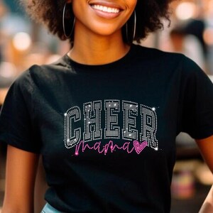 Op de afbeelding: Zwart T-shirt met een strass-ontwerp met de tekst "Cheer Mama" met een roze hart.