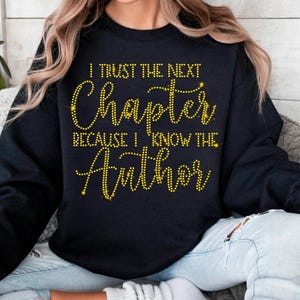 Puede incluir: Sudadera negra con letras de purpurina dorada que dicen "I trust the next chapter because I know the Author".