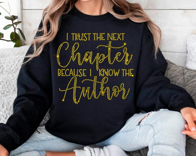 Puede incluir: Sudadera negra con letras de purpurina dorada que dicen "I trust the next chapter because I know the Author".