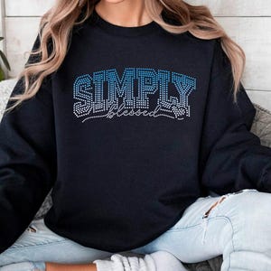May include: Black sweatshirt with the text "SIMPLY blessed" in blue rhinestones.
