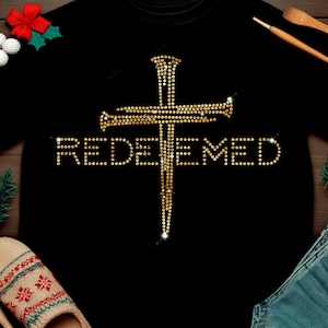 May include: Black t-shirt with a gold rhinestone cross and the word "REDEEMED" in gold rhinestones.