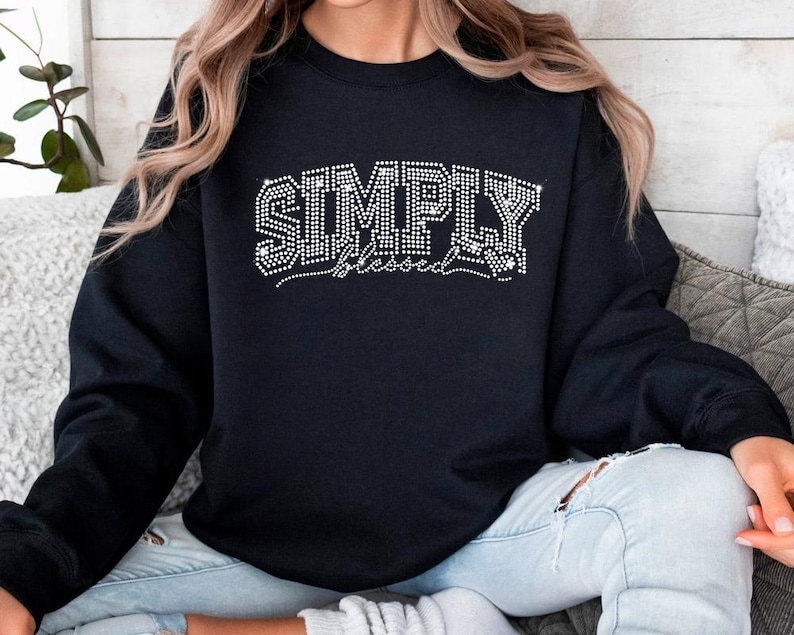 May include: Black sweatshirt with the words "SIMPLY blessed" in white rhinestones.