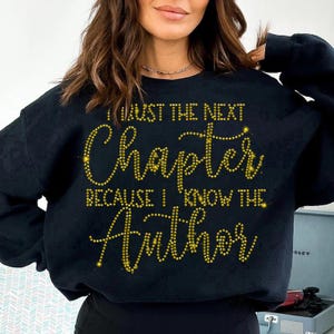 Puede incluir: Sudadera negra con letras de purpurina dorada que dicen "I trust the next chapter because I know the Author".