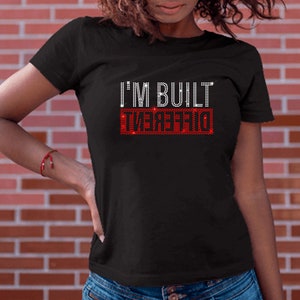 May include: Black t-shirt with the text "I'M BUILT DIFFERENT" in red rhinestones.
