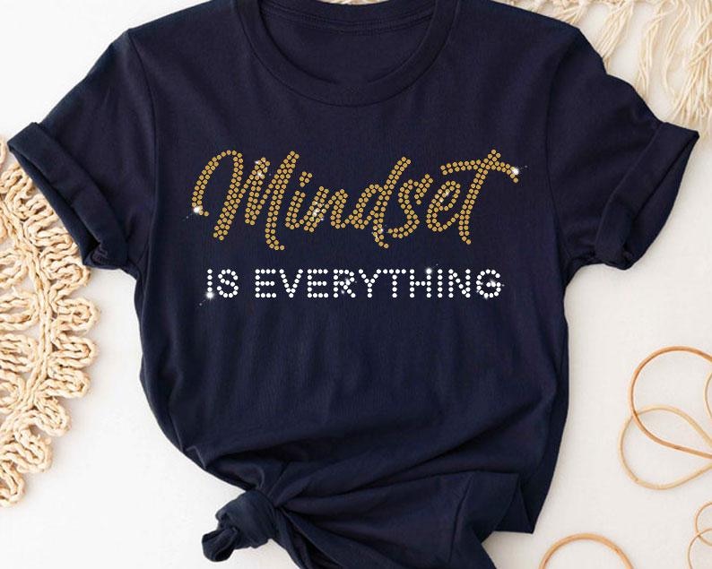 May include: A navy blue t-shirt with the text "Mindset is Everything" in gold glitter lettering.