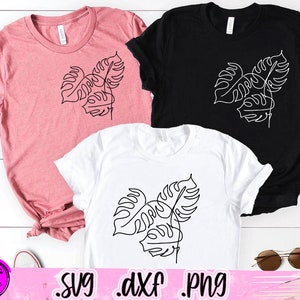 May include: Three different color t-shirts with a line drawing of a monstera leaf on each. The shirts are pink, black, and white.