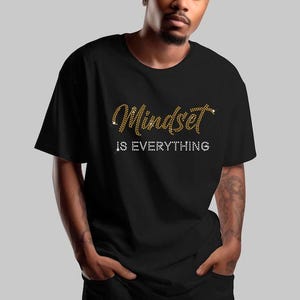 May include: A black t-shirt with the text "Mindset is Everything" in gold and white rhinestones.