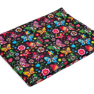 May include: A black fabric with a colourful butterfly and flower pattern. The fabric is folded in half and the pattern is visible on both sides.