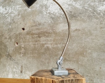 Peut inclure: Une lampe de bureau vintage noire et argentée avec un bras flexible, montée sur une base en bois épaisse.
