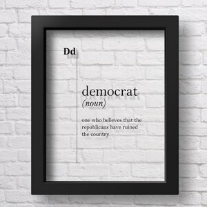 以下が含まれることがあります： 白い背景に黒い文字で「Dd デモクラット（名詞）共和党が国を破滅させたと思っている人」と書かれた、黒い額縁に入ったプリントです。