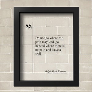 May include: A black framed print with a white background and a quote by Ralph Waldo Emerson: "Do not go where the path may lead, go instead where there is no path and leave a trail."