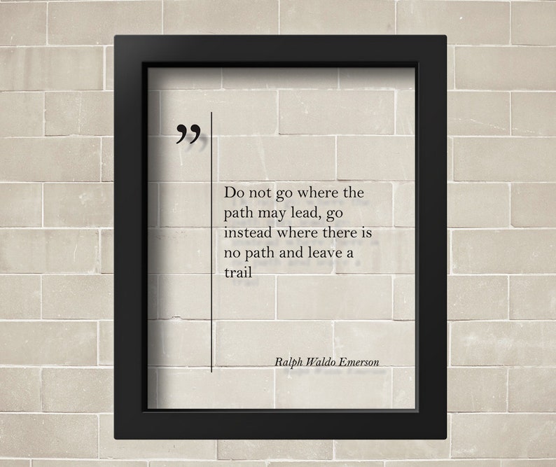 May include: A black framed print with a white background and a quote by Ralph Waldo Emerson: "Do not go where the path may lead, go instead where there is no path and leave a trail."