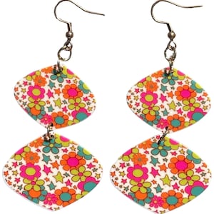 May include: A pair of dangle earrings with a retro floral pattern. Each earring features two diamond-shaped pendants with a white background and a colorful design of flowers and stars in pink, orange, green, and blue. The earrings have silver-colored hooks.