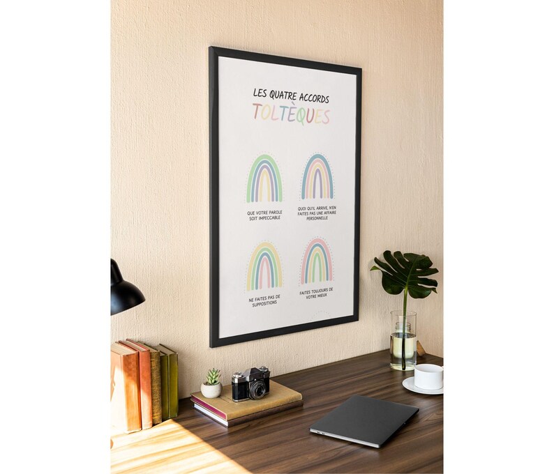 May include: A black framed print with a white background and rainbow illustrations. The text on the print reads "Les Quatre Accords Tolteques". The text below each rainbow reads "Que votre parole soit impeccable", "Que quoi que arrive, faites-en une affaire personnelle", "Ne faites pas de suppositions", and "Faites toujours de votre mieux".