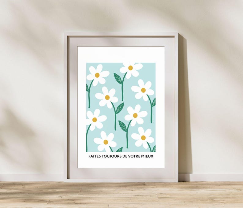 May include: A white framed print with a light blue background and a repeating pattern of white daisies with yellow centers and green stems. The text "FAITES TOUJOURS DE VOTRE MIEUX" is at the bottom of the print.