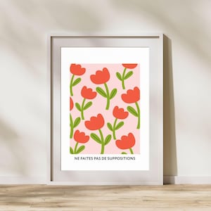 May include: A framed print with a pink background and a repeating pattern of red flowers with green stems. The text "NE FAITES PAS DE SUPPOSITIONS" is at the bottom of the print.