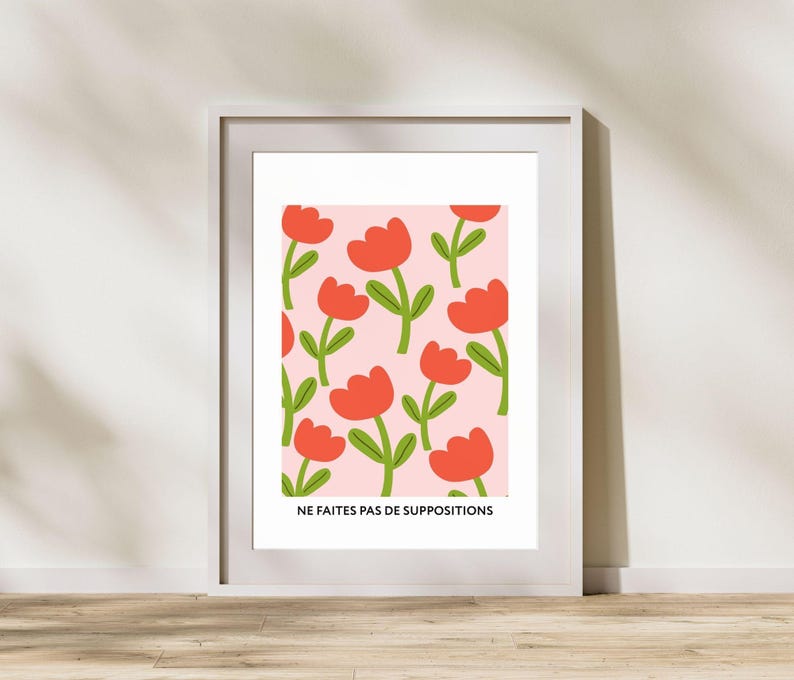 May include: A framed print with a pink background and a repeating pattern of red flowers with green stems. The text "NE FAITES PAS DE SUPPOSITIONS" is at the bottom of the print.
