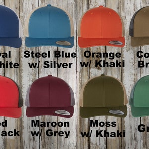 May include: A variety of trucker hats in different colors and mesh back panels. The hats are arranged in two rows of five. The colors include royal blue with white mesh, steel blue with silver mesh, orange with khaki mesh, coyote brown with brown mesh, red with black mesh, maroon with grey mesh, moss green with khaki mesh, and green with grey mesh. The text below each hat identifies the color and mesh color.