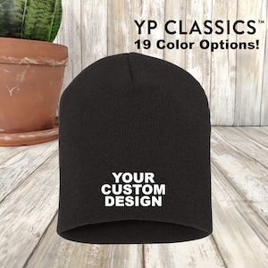 May include: Black knit beanie with the text "YOUR CUSTOM DESIGN" embroidered in white.