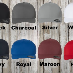 May include: A set of ten baseball caps in various colours, including black, charcoal, silver, white, navy, royal, maroon, and red. The caps are all the same style, with a curved brim and a flat crown.