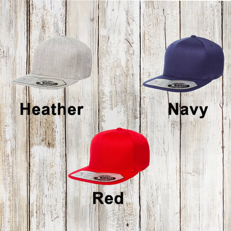 May include: Three flat-brimmed baseball caps in different colours: heather grey, navy blue, and red. Each cap has a black label with the word "1TRUE" on it.