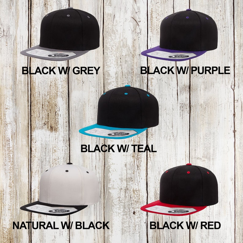 May include: Five different colour variations of a black and white baseball cap. The caps are all flat-brimmed and have a contrasting colour under the brim. The colours are black with grey, black with purple, black with teal, natural with black, and black with red.