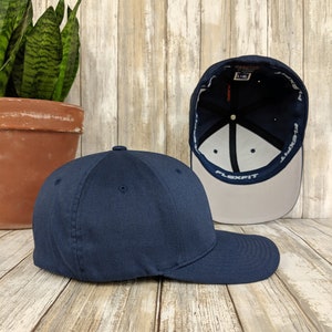 K&ouml;nnte beinhalten: Eine marineblaue Baseballkappe mit einem verstellbaren Flexfit-Band. Die Kappe wird von der Seite gezeigt und das Innere der Kappe ist sichtbar.