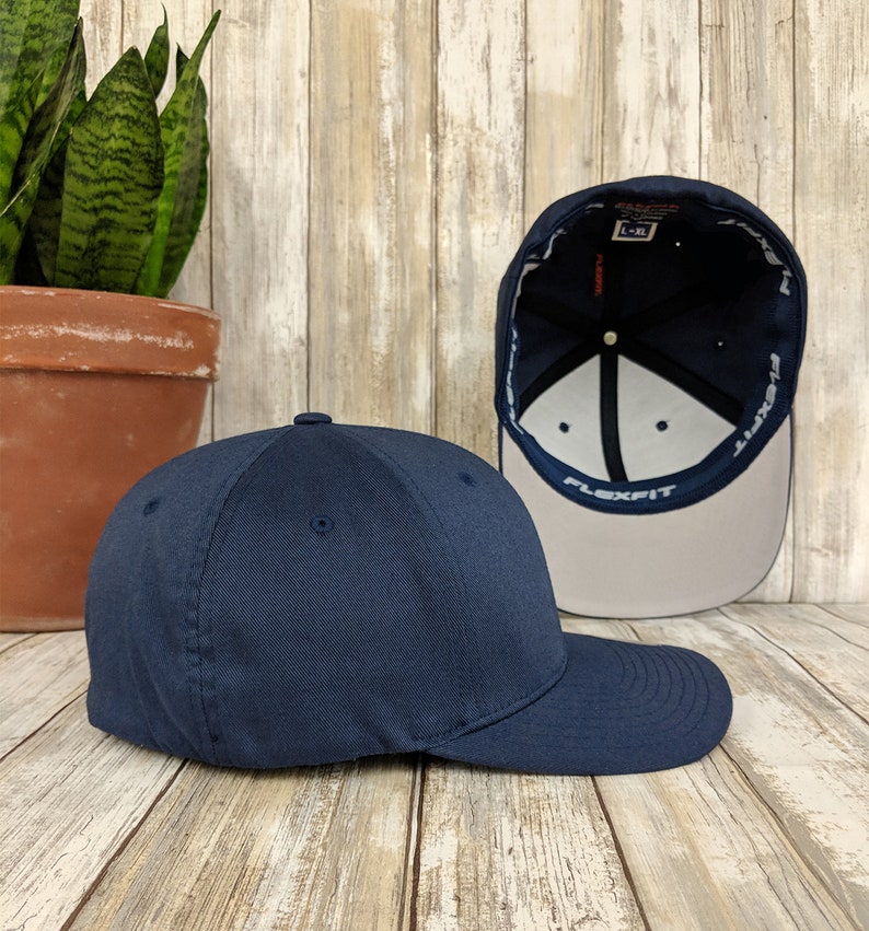 K&ouml;nnte beinhalten: Eine marineblaue Baseballkappe mit einem verstellbaren Flexfit-Band. Die Kappe wird von der Seite gezeigt und das Innere der Kappe ist sichtbar.