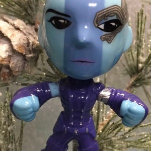 May include: A blue and purple Guardians of the Galaxy Christmas ornament featuring a character with a blue face and purple outfit.