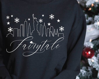 May include: Black sweatshirt with a white outline of the New York City skyline and the word "Fairytale" in a cursive font. The skyline includes the Statue of Liberty and snowflakes.