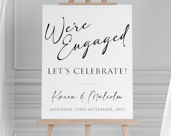 Puede incluir: Un cartel blanco con texto negro anunciando una fiesta de compromiso para Karen y Malcolm. El cartel dice "We're Engaged! Let's Celebrate!" e incluye la fecha "Saturday, 23rd September, 2023".