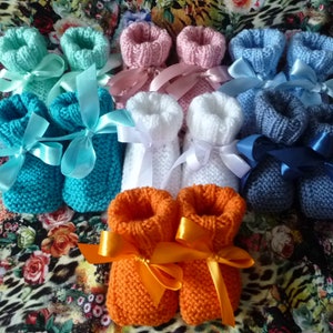 Peut inclure: Un ensemble de dix chaussons en tricot pour bébé dans différentes couleurs, notamment turquoise, bleu clair, blanc, rose et orange. Chaque chausson est orné d'un ruban en satin noué autour de la cheville.