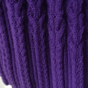 May include: Purple knitted fabric with a cable knit pattern.