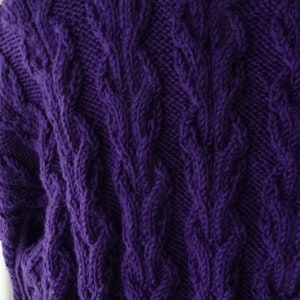 May include: Purple knitted sweater with a cable knit pattern.
