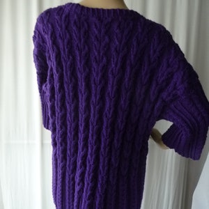 May include: Purple cable knit sweater with a loose fit and short sleeves.