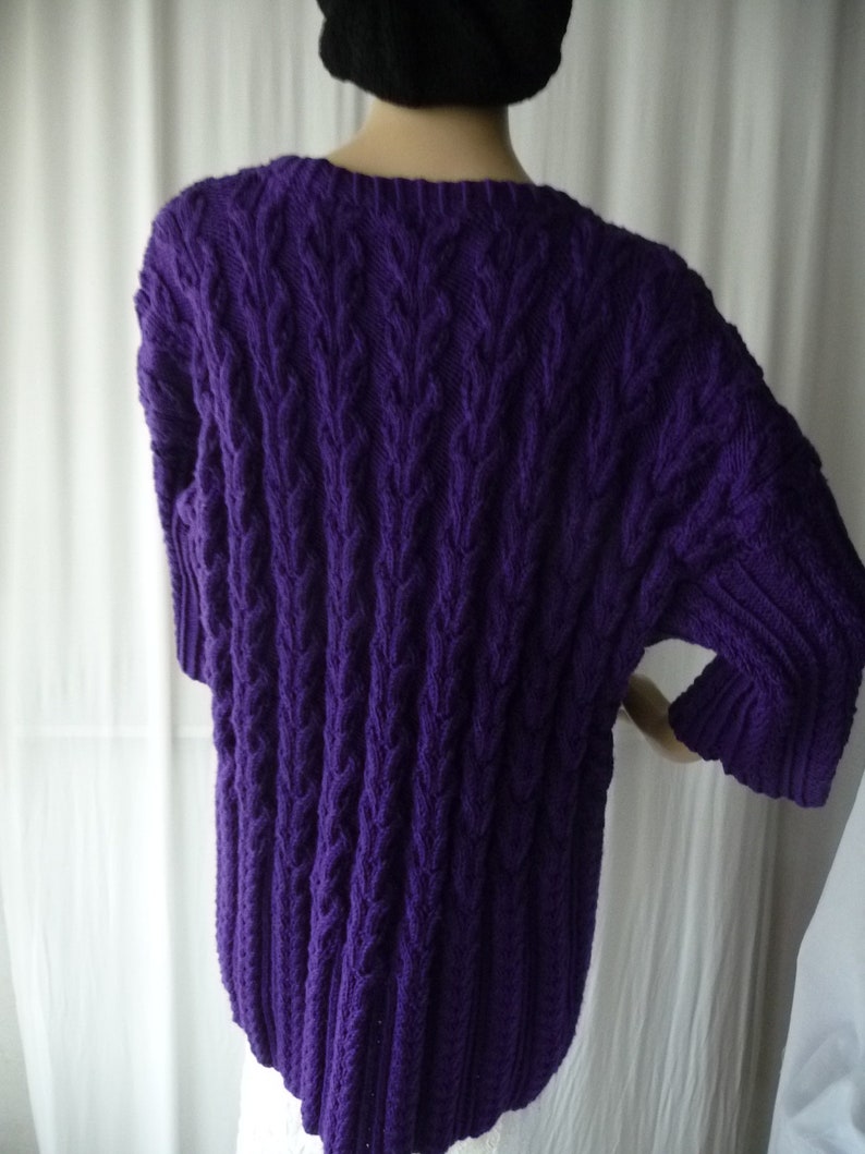 May include: Purple cable knit sweater with a loose fit and short sleeves.