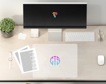 May include: A white desk mat with a colorful monogram "CTS" in a circle. The mat is on a light wood desk with a computer monitor, keyboard, mouse, plant, and papers.