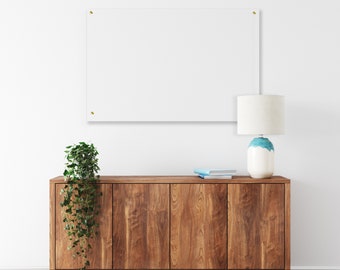 May include: A wooden cabinet with four doors and a light brown finish. A potted plant with green leaves hangs over the cabinet. A white lamp with a cream-colored shade sits on top of the cabinet.